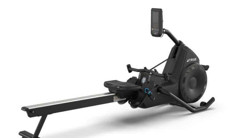 A black rowing machine with a sleek, modern design features a padded seat, footrests, a flywheel, and an upright digital display, set against a plain white background.